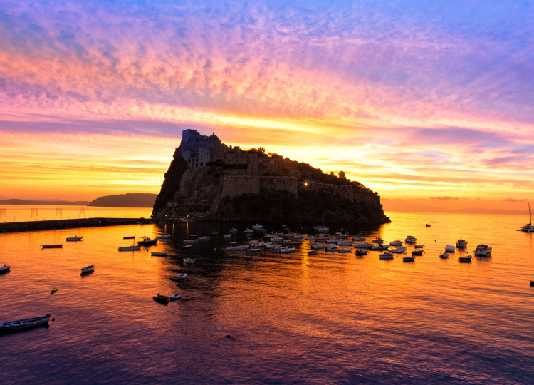 Quando da dietro al Castello Aragonese l’alba colora il cielo e il mare che abbracciano l’isola grande